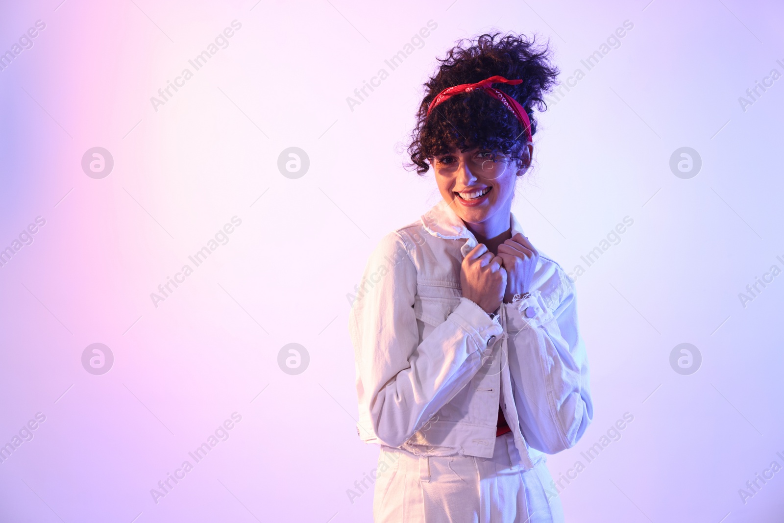 Photo of Beautiful young woman posing on color background in neon lights. Space for text