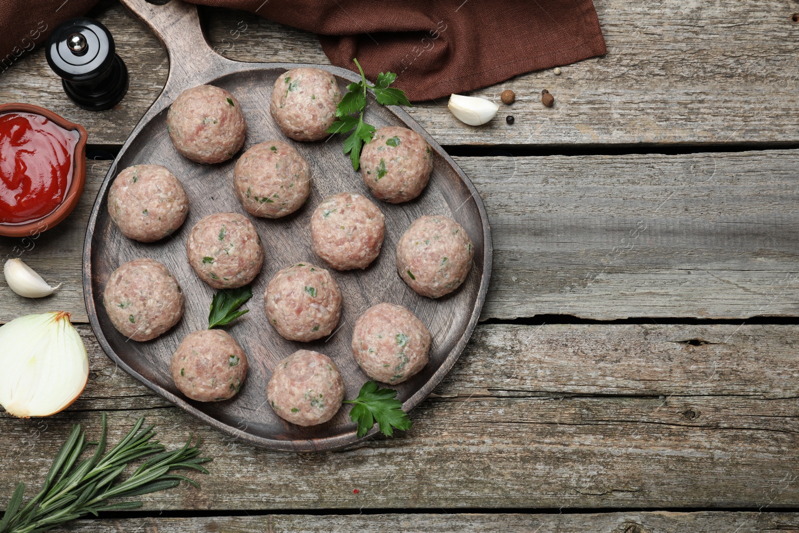 Photo of Many fresh raw meatballs and ingredients on wooden table, flat lay. Space for text