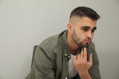 Photo of Portrait of sad man near light grey wall. Space for text