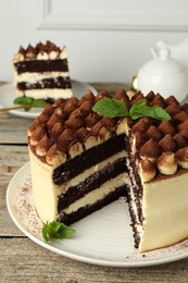 Photo of Delicious tiramisu cake with mint leaves on wooden table