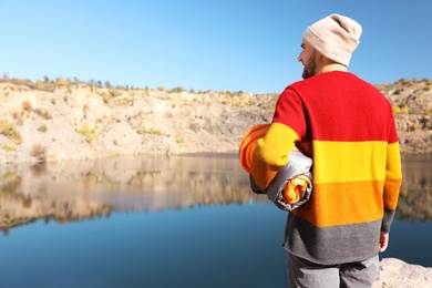 Male camper with sleeping bag near beautiful lake. Space for text