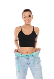 Photo of Slim woman in oversized jeans with measuring tape on white background. Weight loss