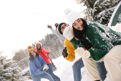 Group of friends playing snowballs outdoors. Winter vacation