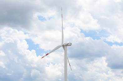 Photo of Modern wind turbine against cloudy sky, closeup. Alternative energy source