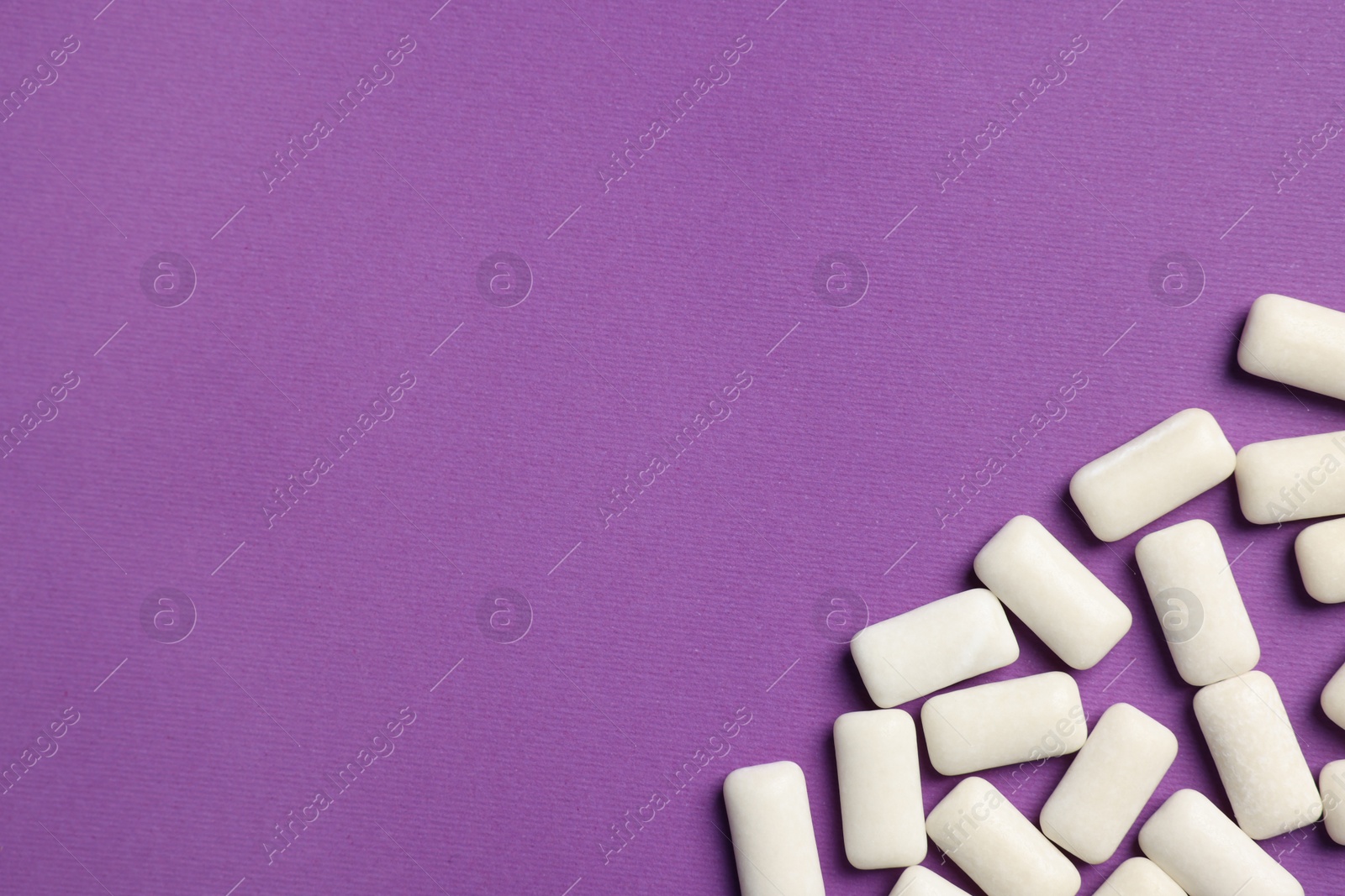 Photo of Tasty white bubble gums on purple background, flat lay. Space for text