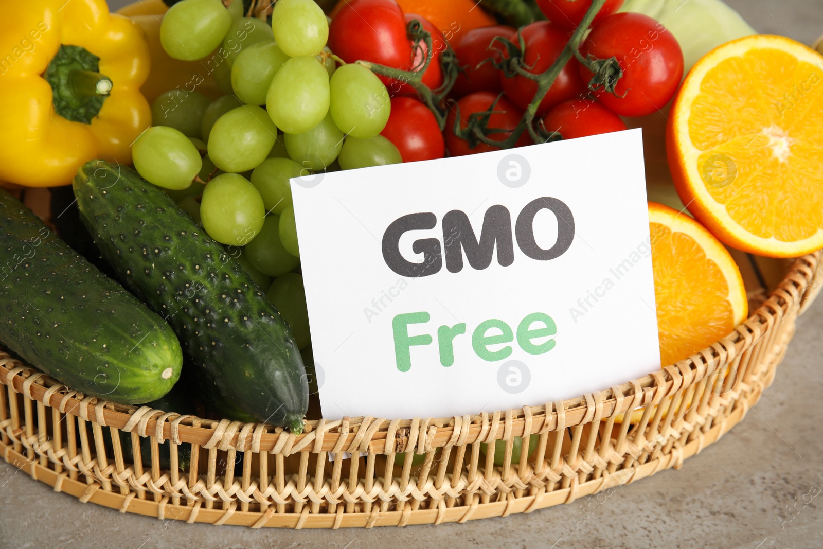 Photo of Tasty fresh GMO free products and paper card on light grey table, closeup