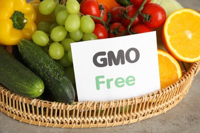 Photo of Tasty fresh GMO free products and paper card on light grey table, closeup