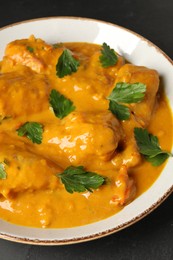 Photo of Tasty chicken curry with parsley on black table, closeup