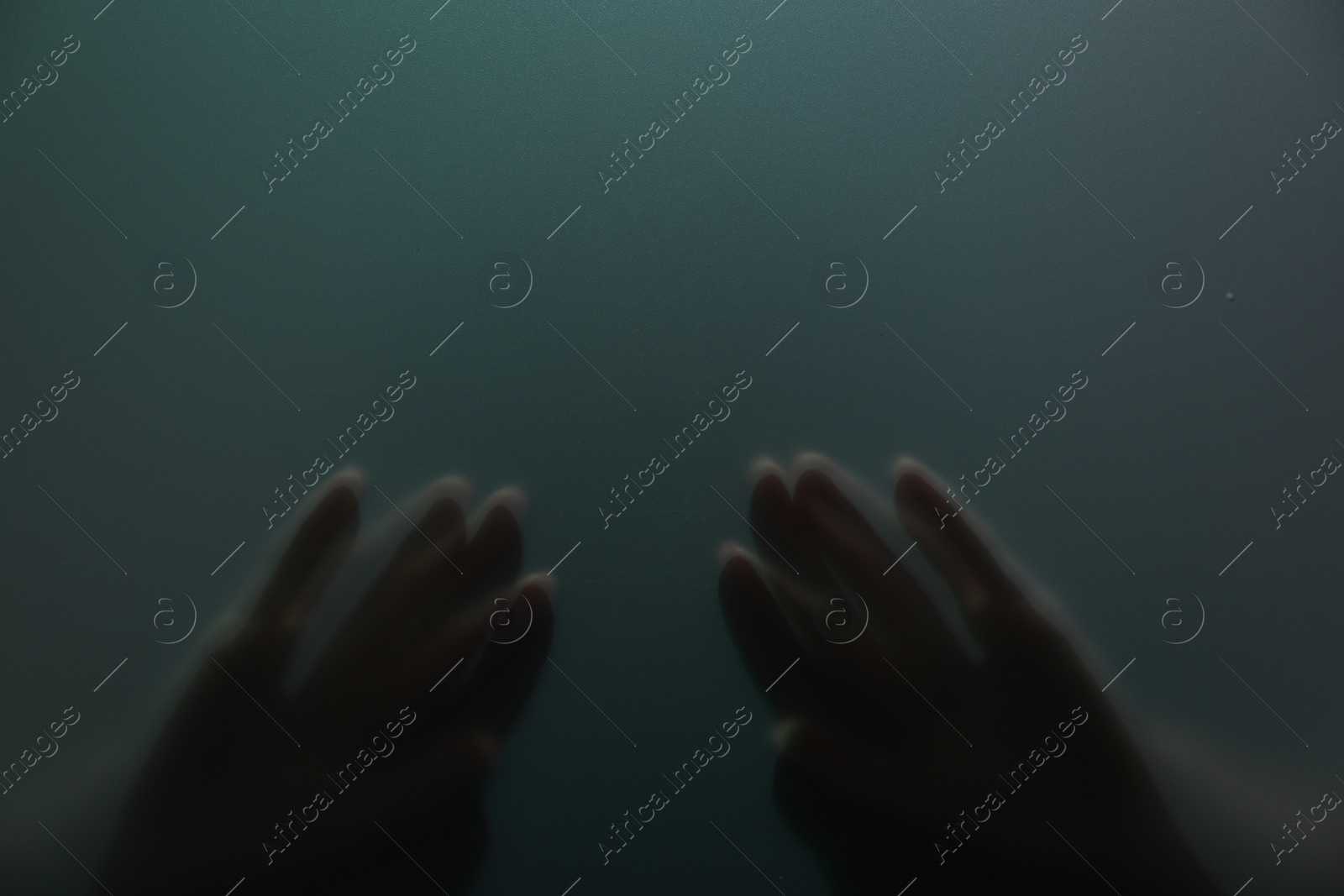 Photo of Silhouette of creepy ghost behind glass against color background, closeup. Space for text