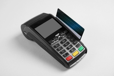 Modern payment terminal with credit card on grey background