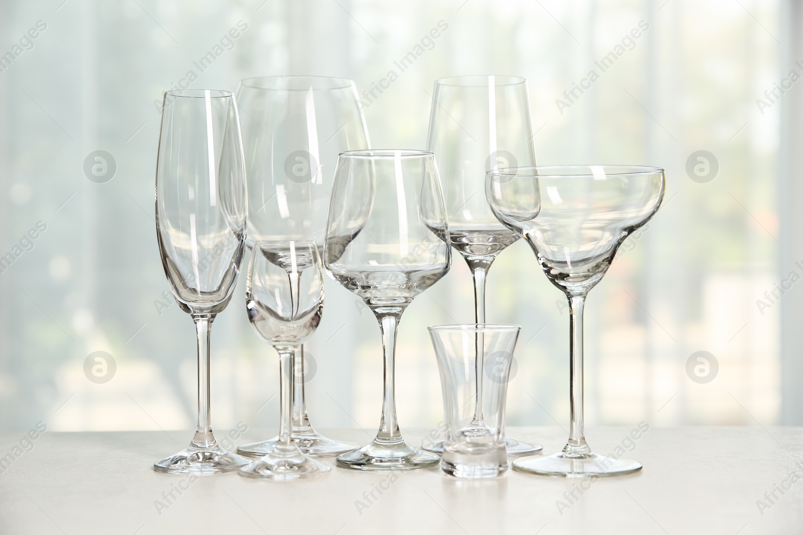 Photo of Different elegant empty glasses on grey table indoors