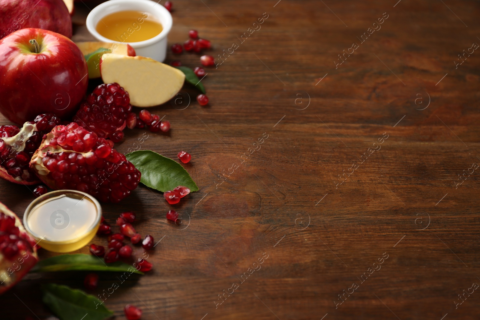 Photo of Honey, apples and pomegranate on wooden table, space for text. Rosh Hashanah holiday