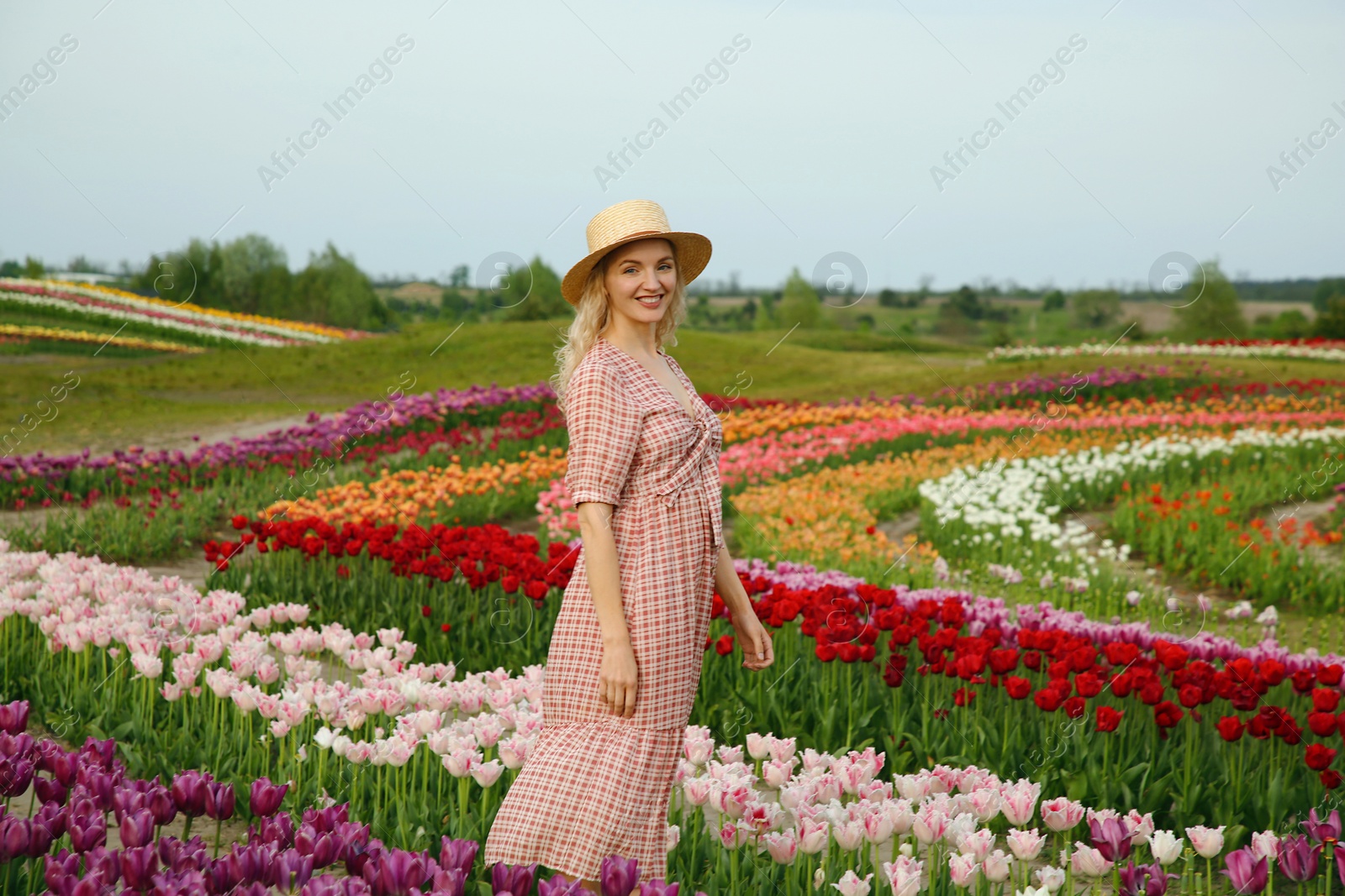 Photo of Happy woman in beautiful tulip field outdoors