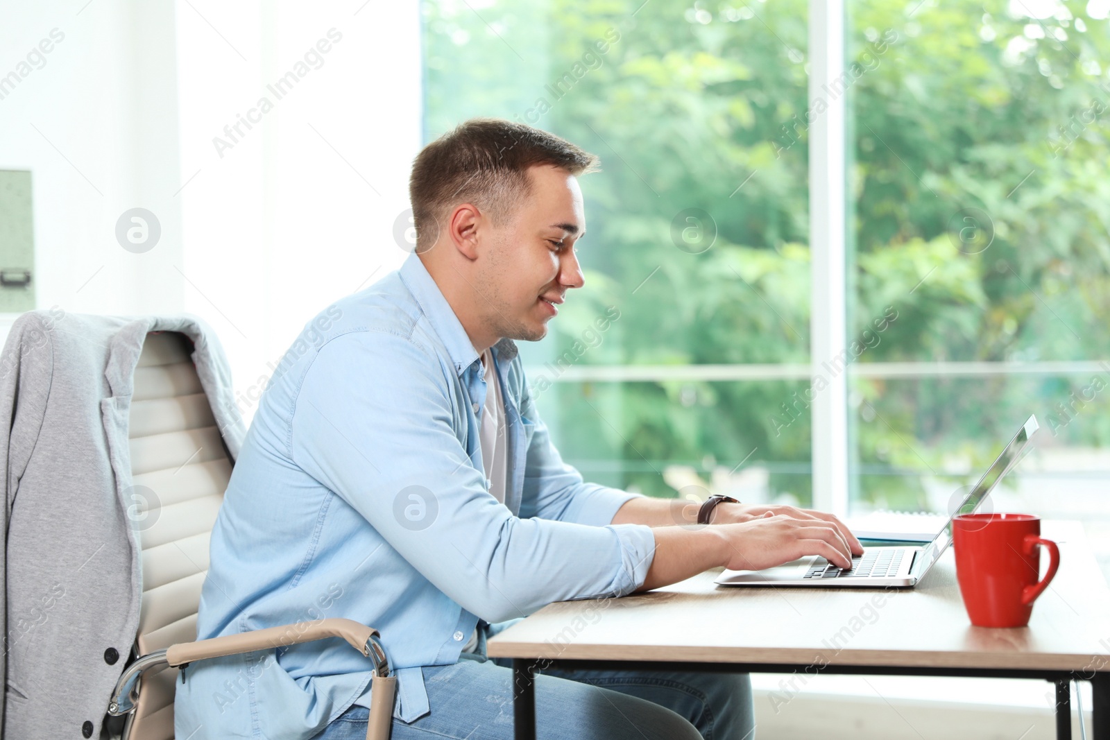 Photo of Young man working with laptop in home office