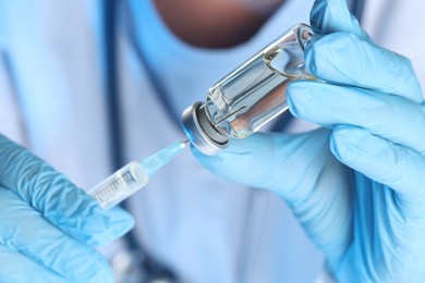 Photo of Doctor filling syringe with medication from glass vial, closeup