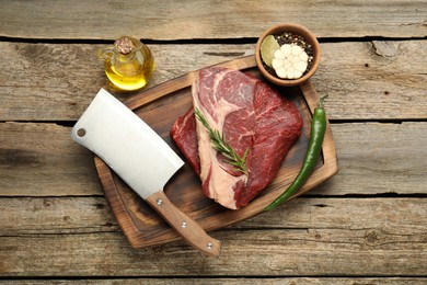Photo of Fresh raw beef cut, spices and butcher knife on wooden table, top view