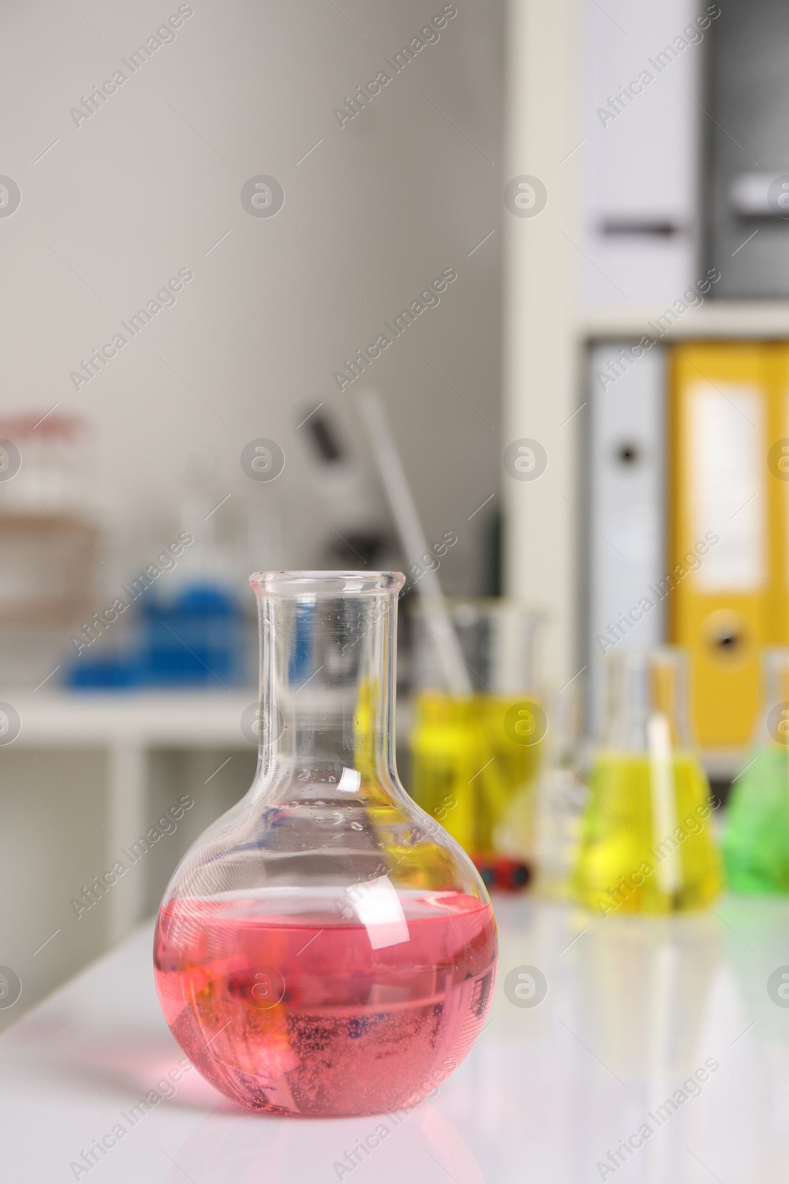 Photo of Laboratory analysis. Flask with pink liquid on white table