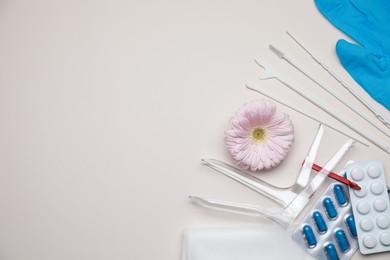 Photo of Gynecological tools, pills and gerbera flower on beige background, flat lay. Space for text