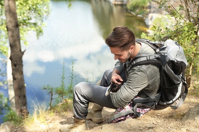 Photo of Young man with cute cat near lake. Camping season