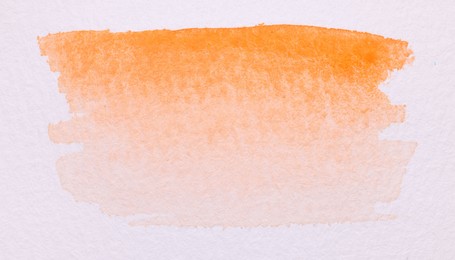 Photo of Abstract orange watercolor painting on white paper, top view