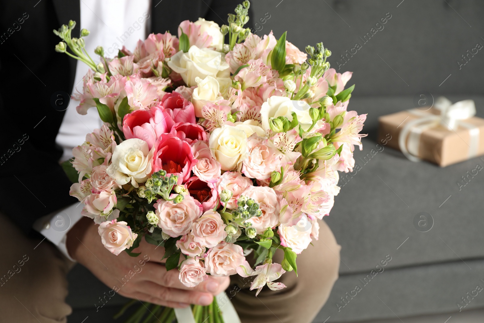 Photo of Man with beautiful bouquet of flowers on sofa indoors, closeup