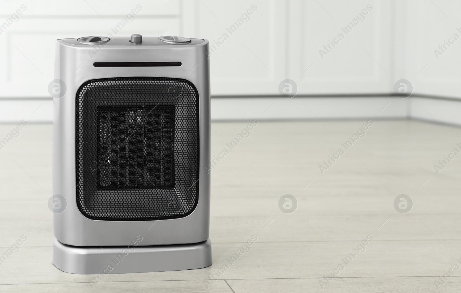 Photo of Modern electric fan heater on floor in kitchen. Space for text