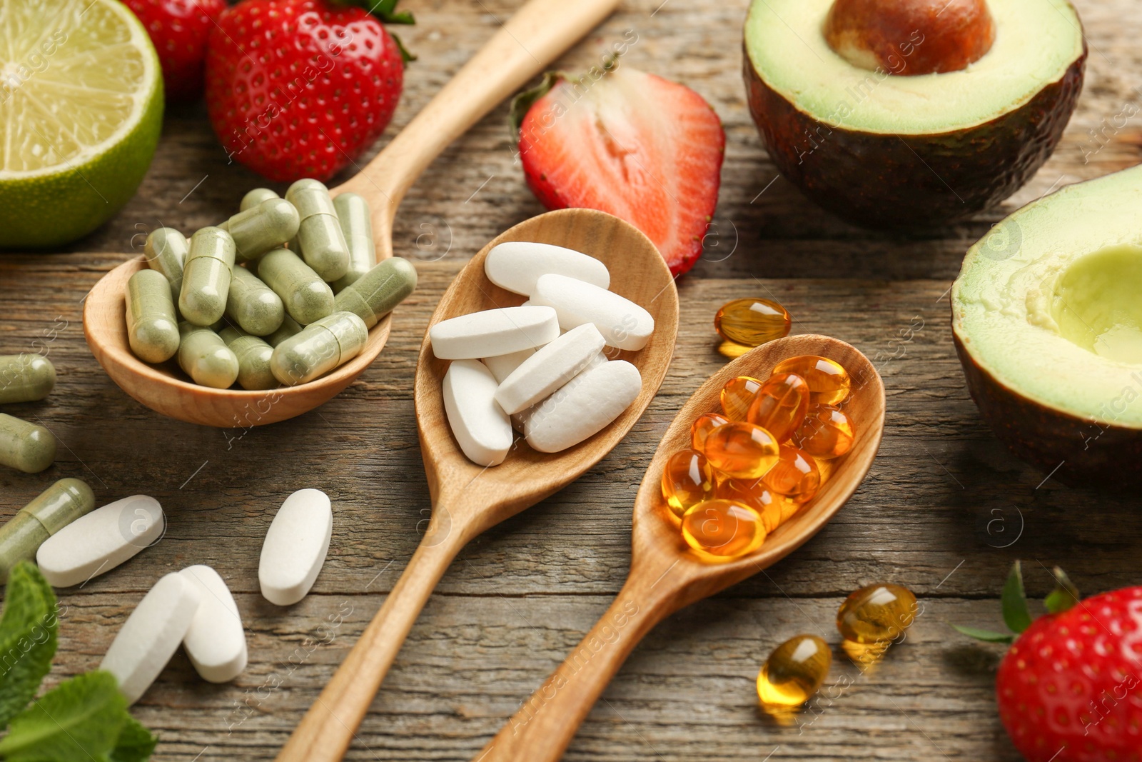 Photo of Different vitamin pills and fresh fruits on old wooden table