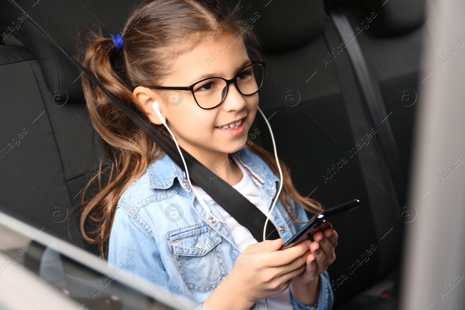 Photo of Cute little girl listening to audiobook in car