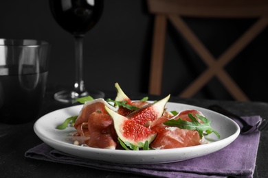 Photo of Delicious figs and proscuitto on black table