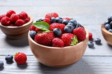Photo of Different fresh ripe berries on light grey wooden table, closeup