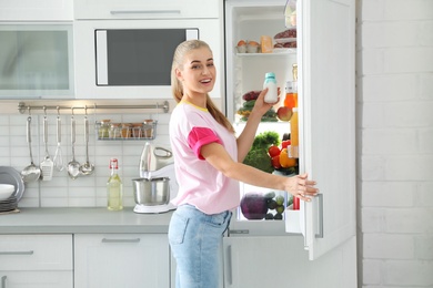 Woman taking products out of refrigerator in kitchen