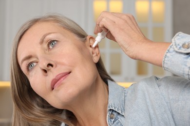 Woman applying medical ear drops at home