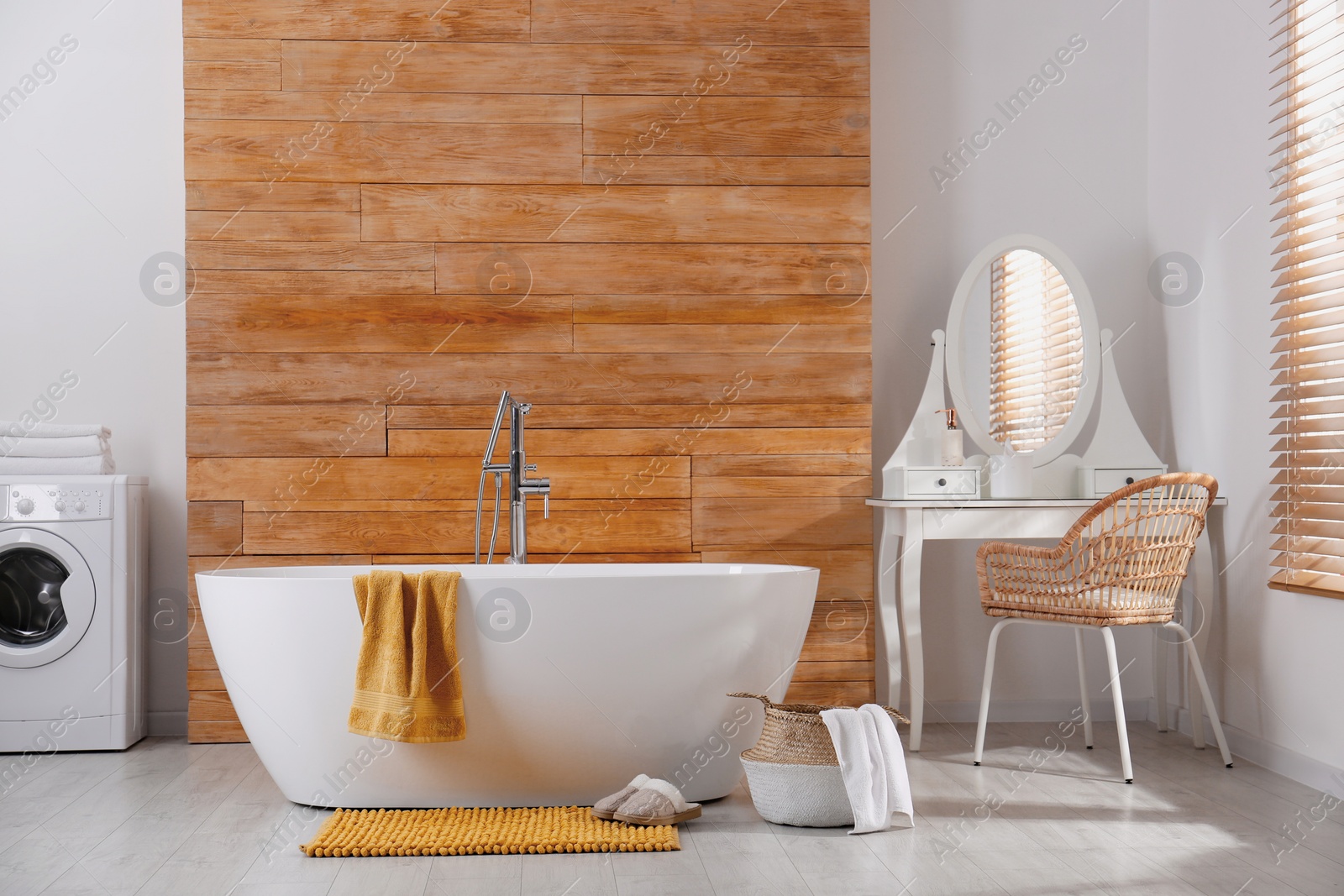 Photo of Soft orange mat and slippers on floor near tub in bathroom. Interior design