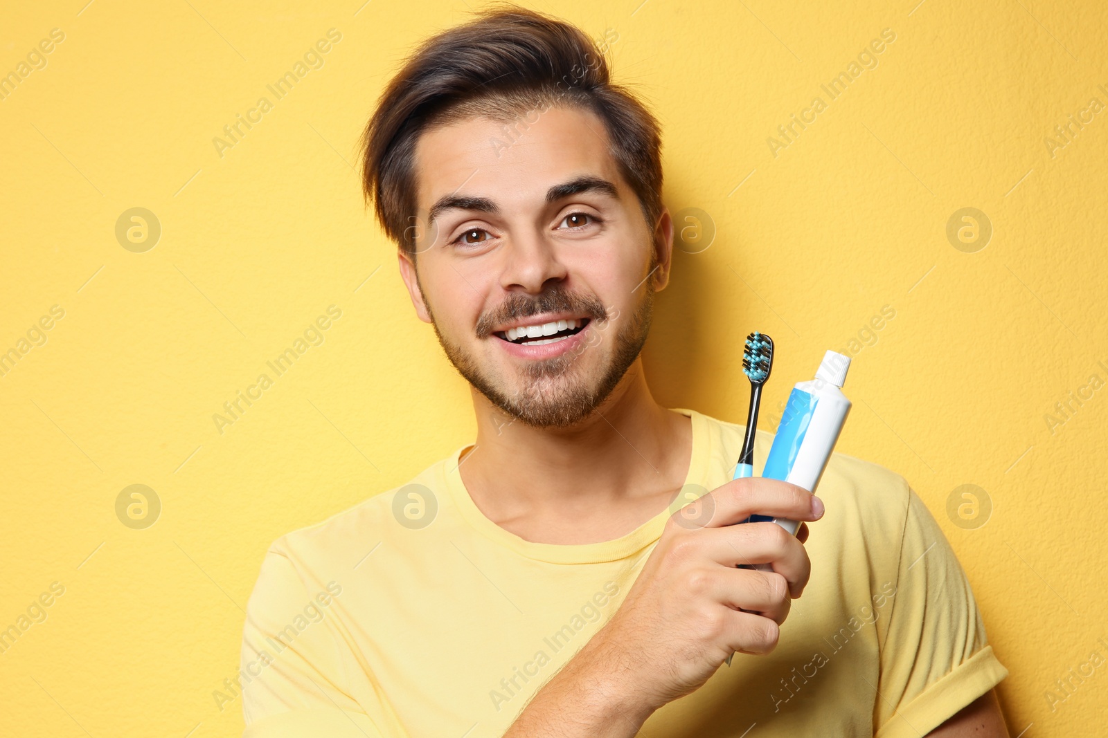 Photo of Portrait of young man with toothbrush and paste on color background