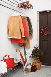 Photo of Christmas wreath hanging on wooden door, festive decoration and outwear indoors