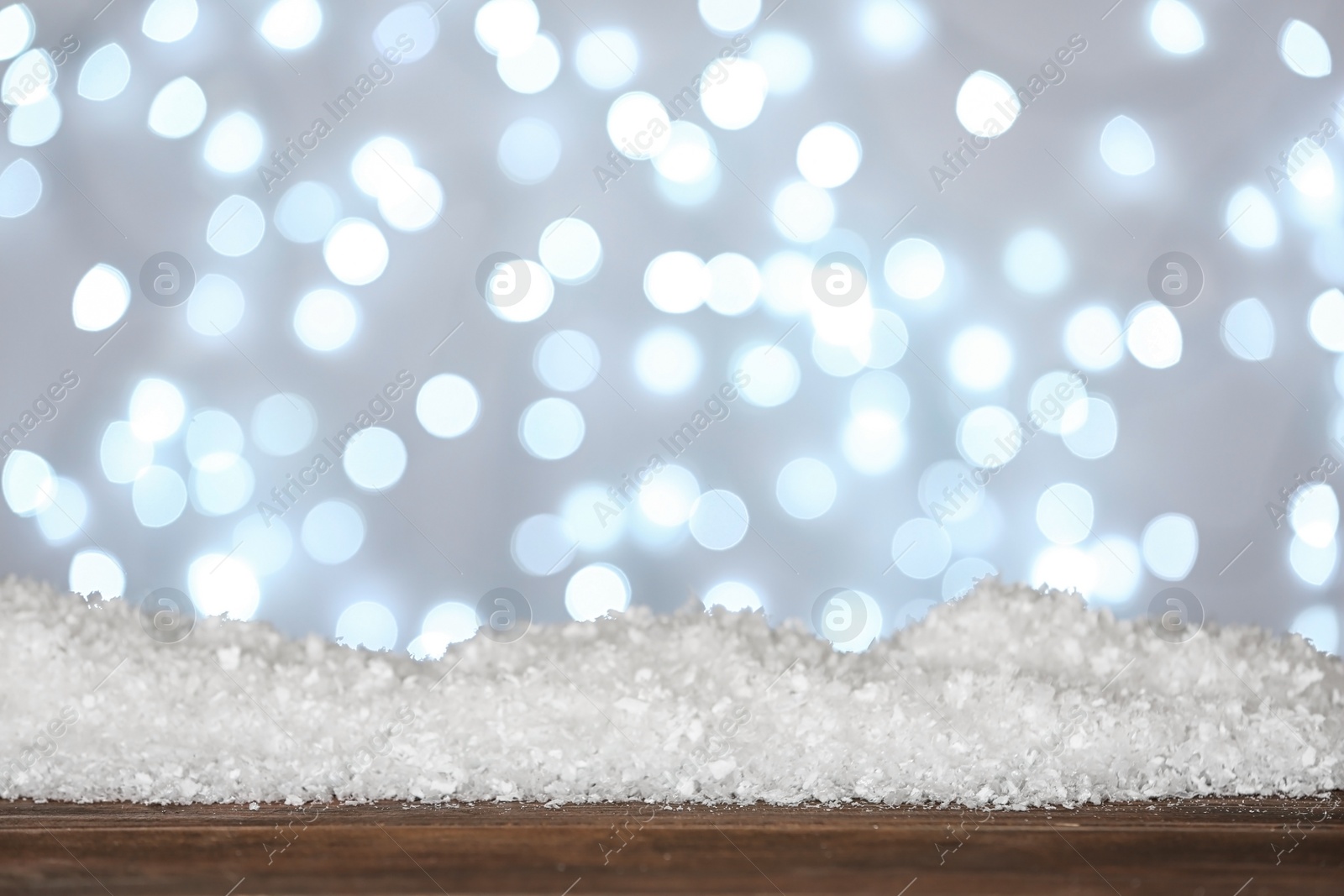 Photo of Heap of snow on wooden surface against blurred background. Christmas season