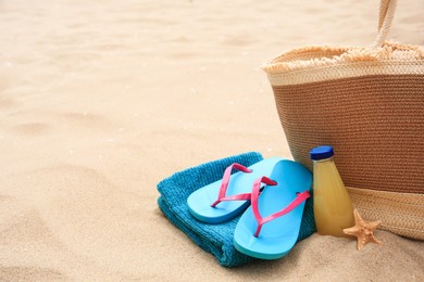 Beach accessories, bottle of refreshing drink and starfish on sand, space for text