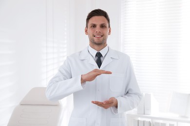 Photo of Happy male dentist holding something in clinic