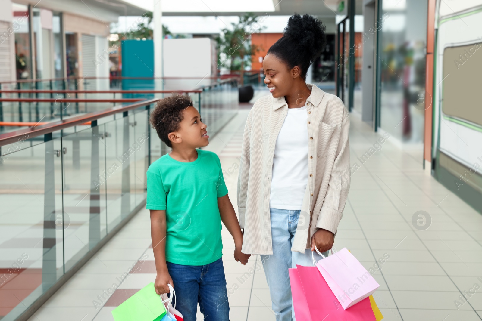 Photo of Family shopping. Happy mother and son with colorful bags in mall