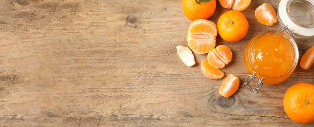 Flat lay composition with tasty tangerine jam on wooden table. Space for text