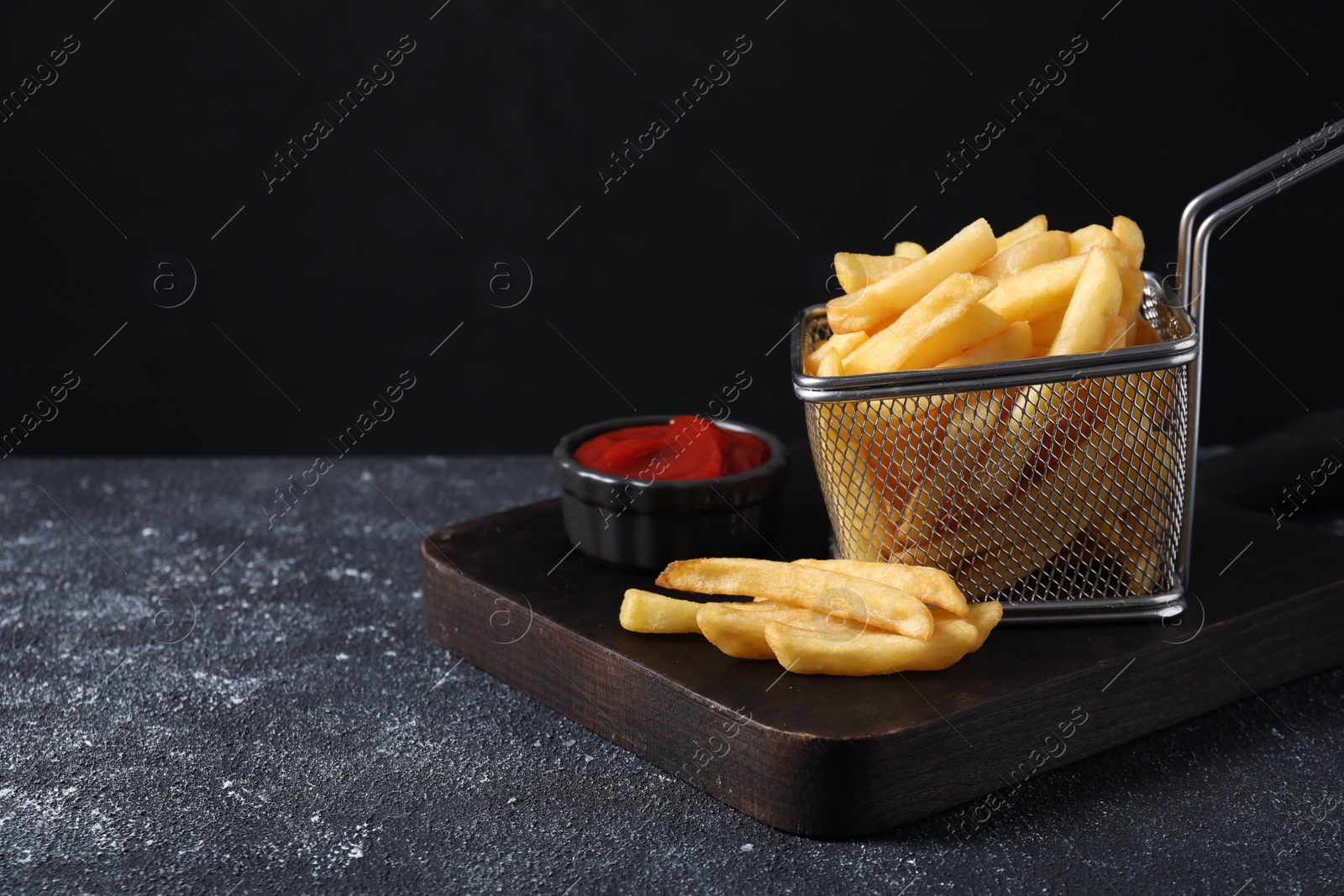 Photo of Tasty French fries and ketchup on grey textured table. Space for text