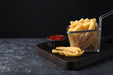 Photo of Tasty French fries and ketchup on grey textured table. Space for text