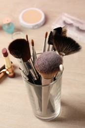 Set of professional brushes and makeup products on wooden table