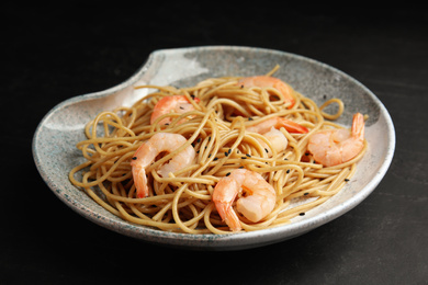 Photo of Plate of tasty buckwheat noodles with shrimps on black table