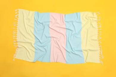 Photo of Crumpled striped beach towel on yellow background, top view
