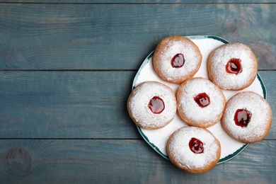 Photo of Hanukkah doughnuts with jelly and sugar powder served on blue wooden table, top view. Space for text