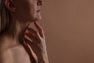 Photo of Beautiful woman touching her neck on beige background, closeup. Space for text