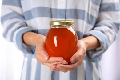 Woman holding glass jar with fresh sweet honey, closeup