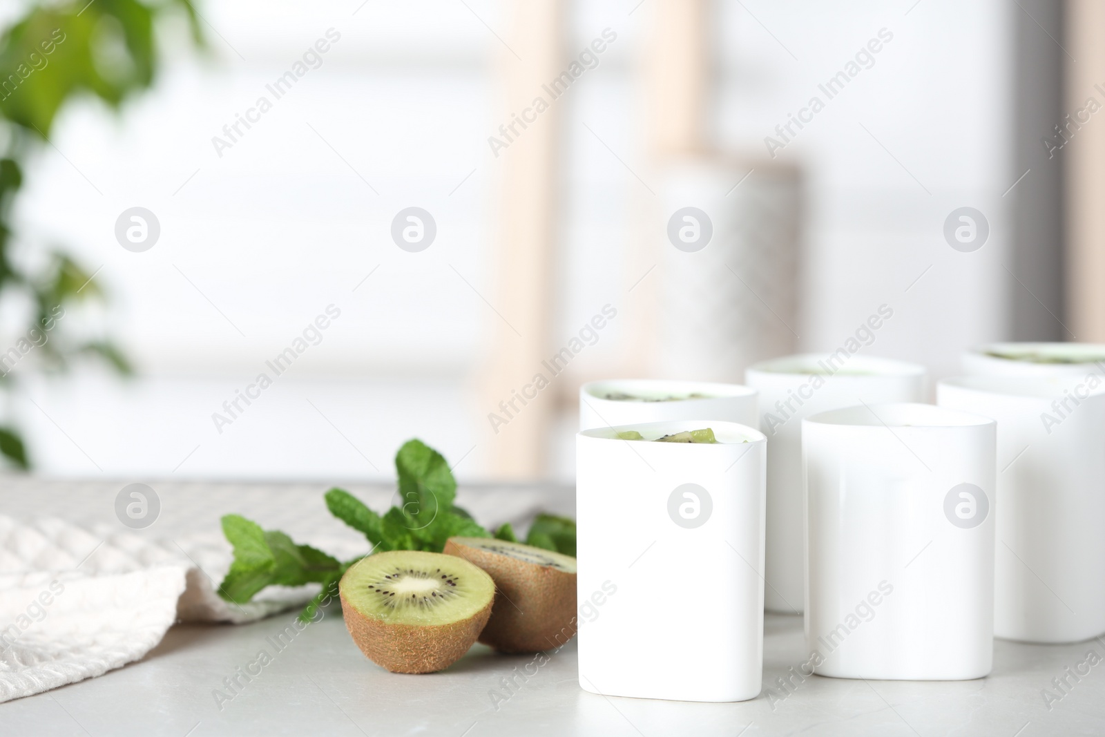 Photo of Cups for homemade yogurt and fresh kiwi on table in kitchen. Recipe for multi cooker