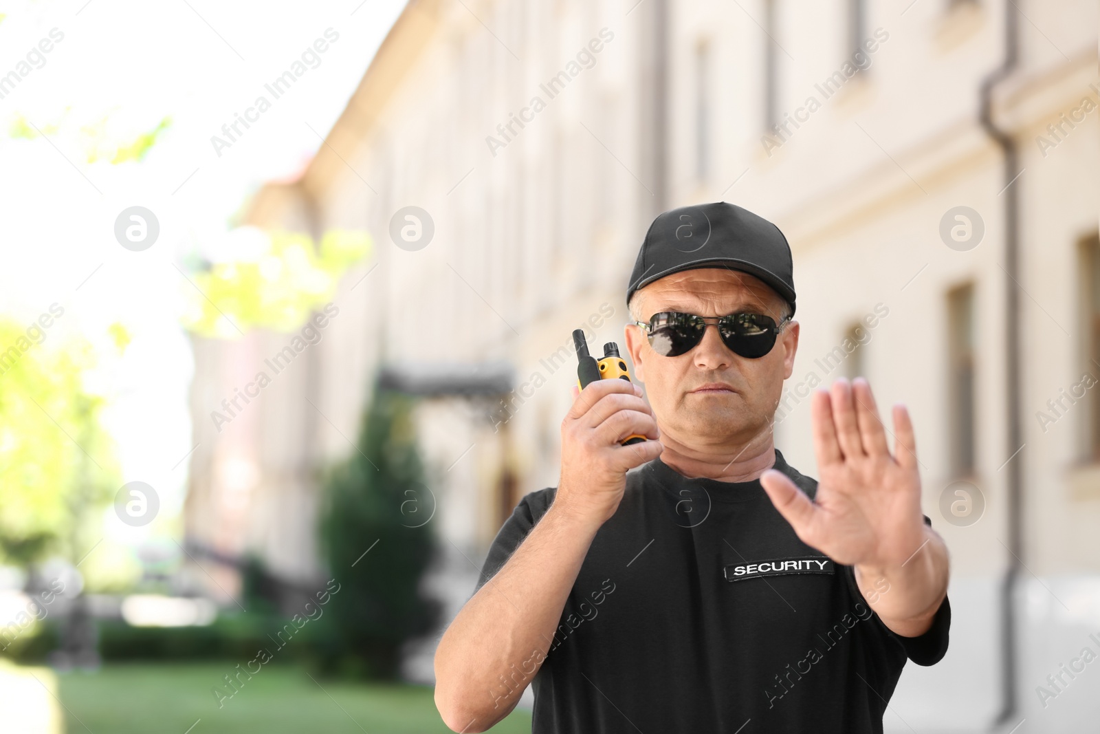 Photo of Male security guard using portable radio transmitter outdoors